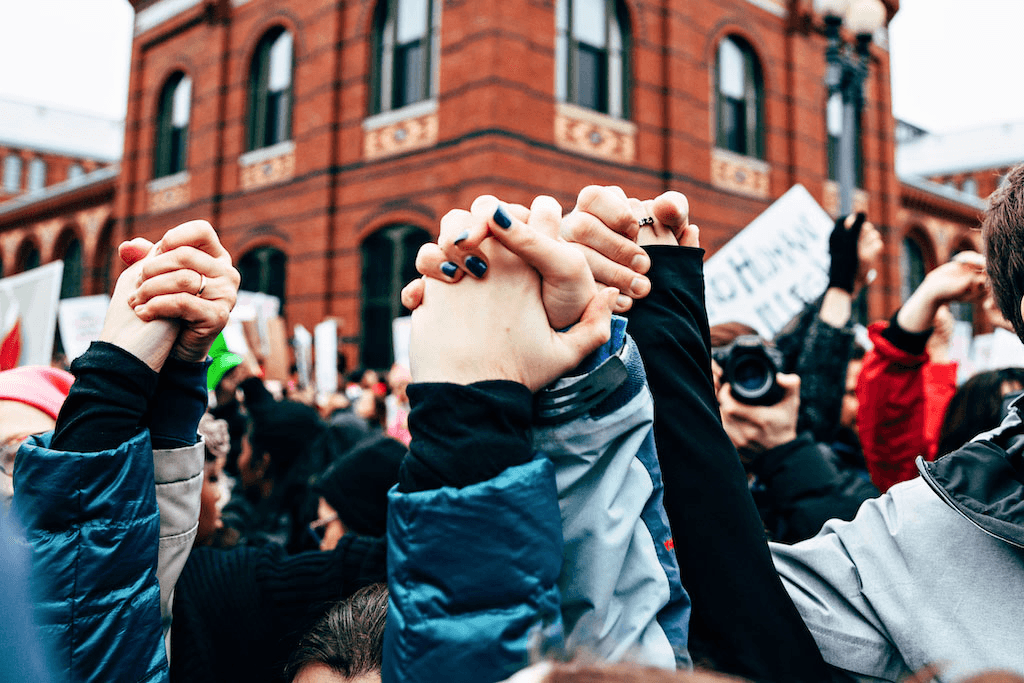 People raising clasped hands together at a demonstration